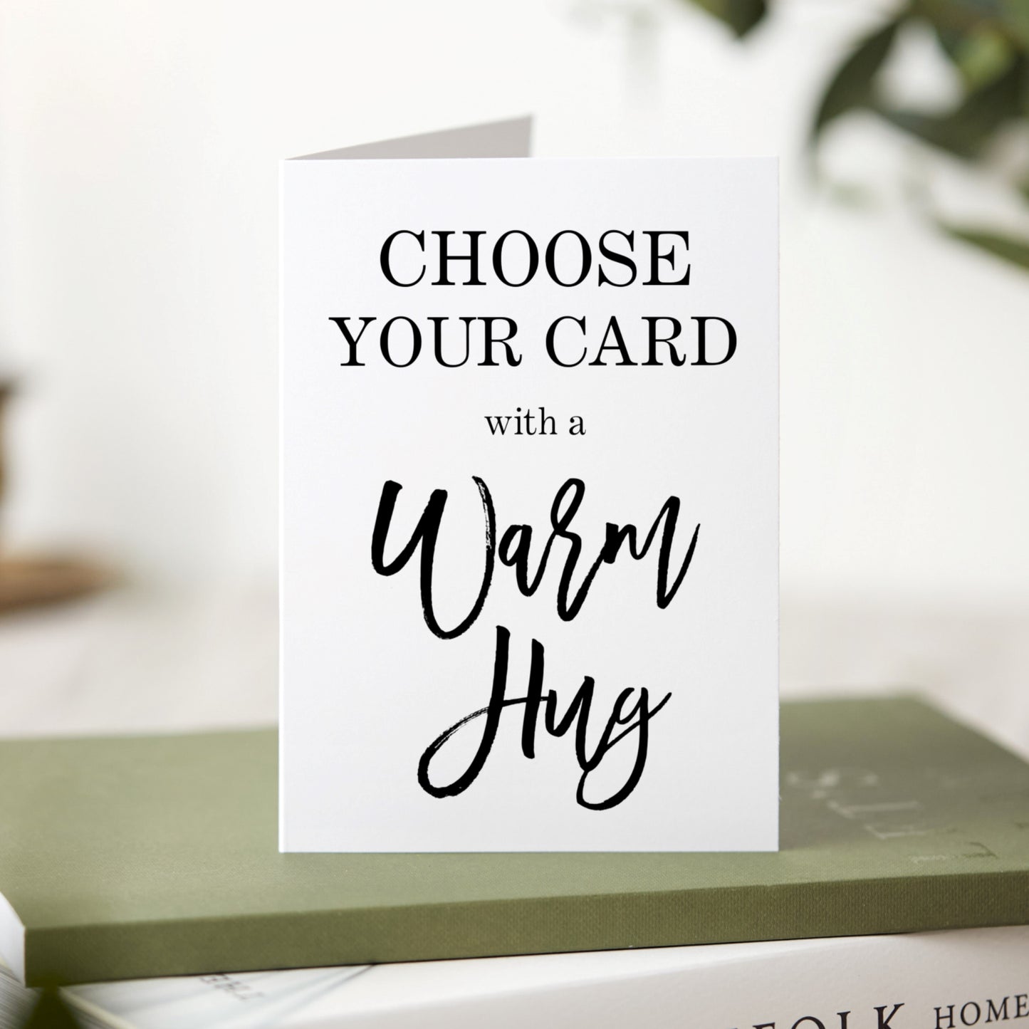 Greeting card with text 'Choose Your Card with a Warm Hug' on a blurred background