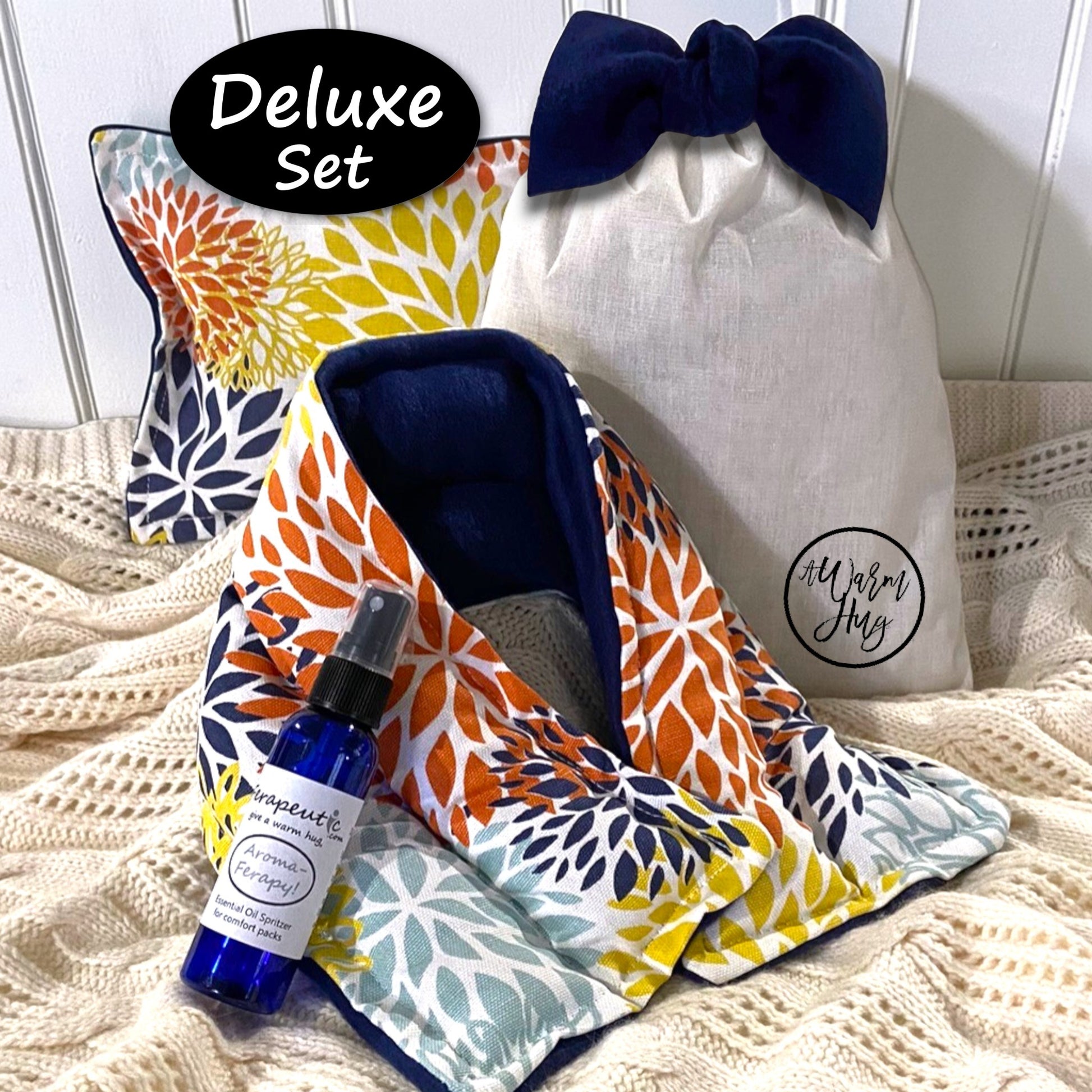 Deluxe set with blooms heating pads, aromatherapy bottle, and drawstring bag on a textured surface.