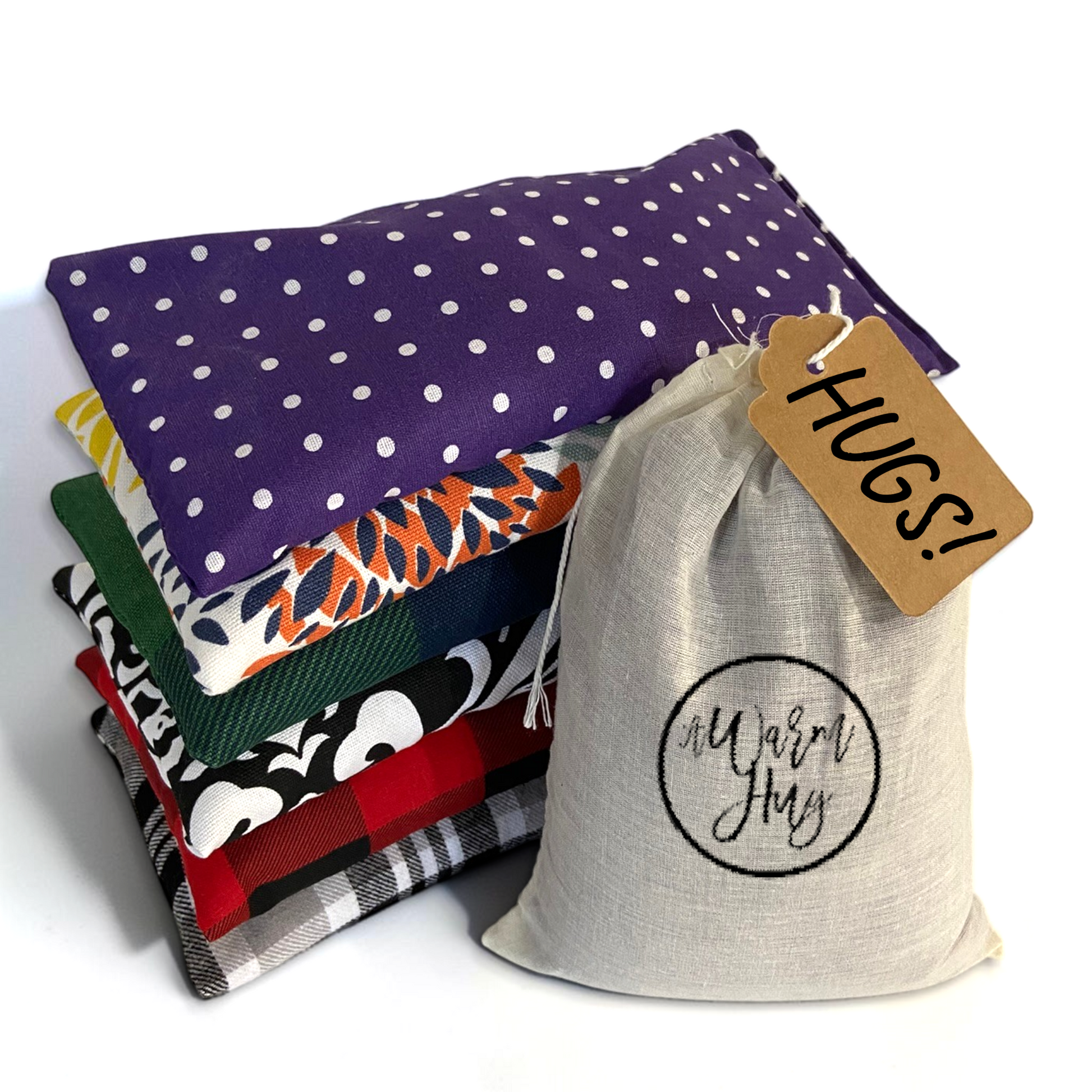 Stack of warm hug mini gift heat pads with gift bag and gift tag that reads, HUGS!