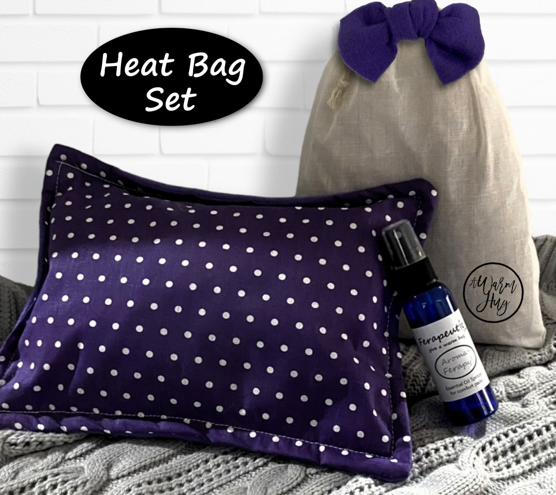 Heat bag set with a purple polka dot pillow, gray drawstring bag, and bottle of essential oil spray on a textured surface.
