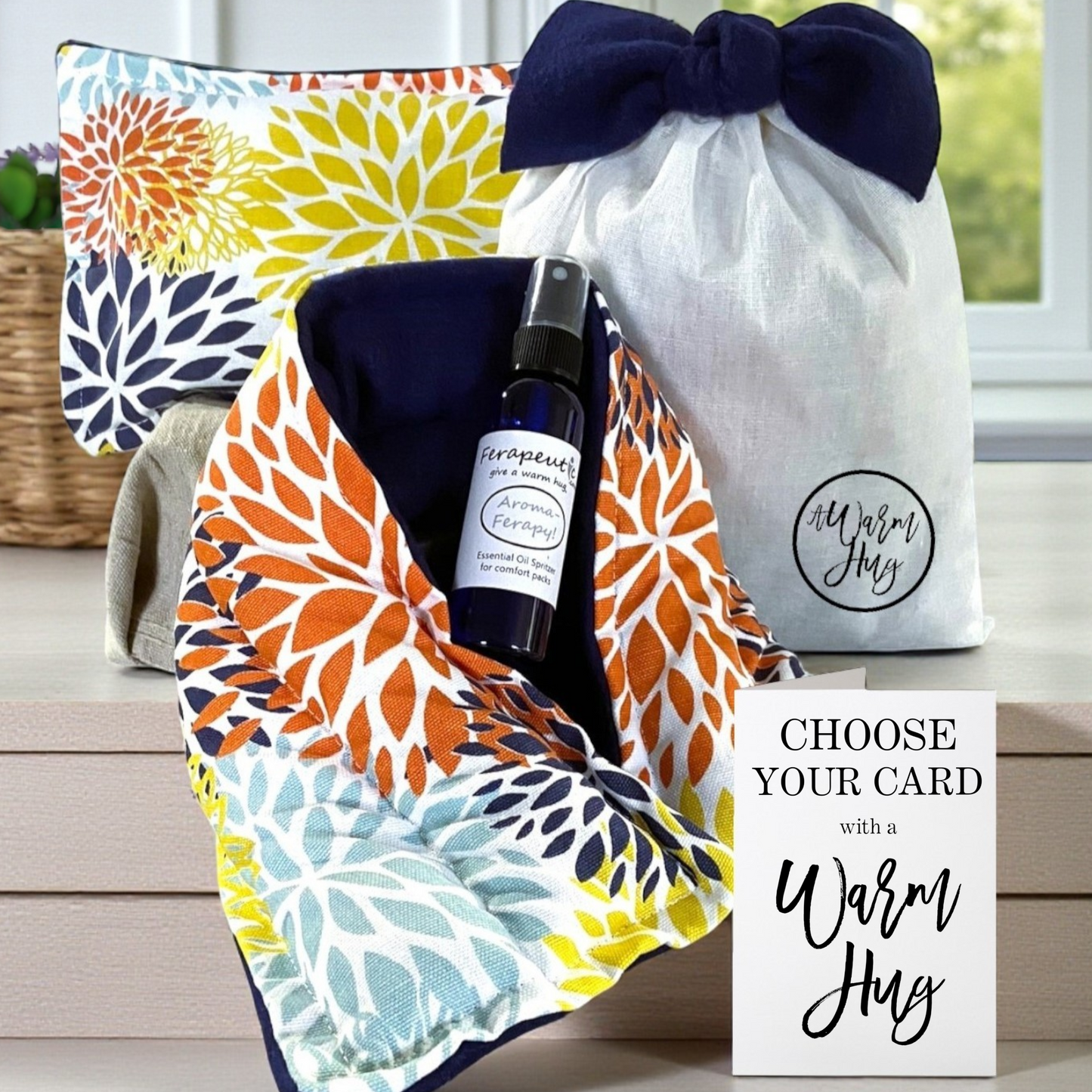 Gift set with floral-patterned microwave neck wrap, heat bag, bottle, and warm hug card on a wooden surface.
