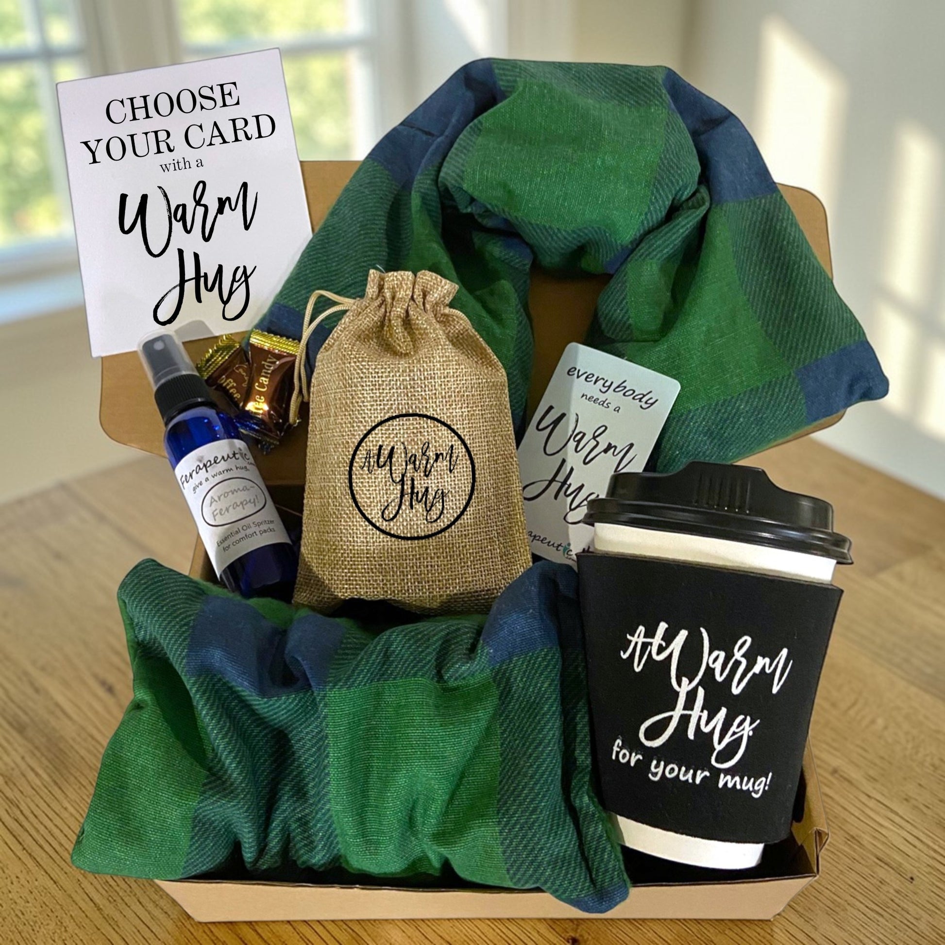 Gift basket with a green plaid microwave heat pads, coffee cup, and other items on a wooden surface.