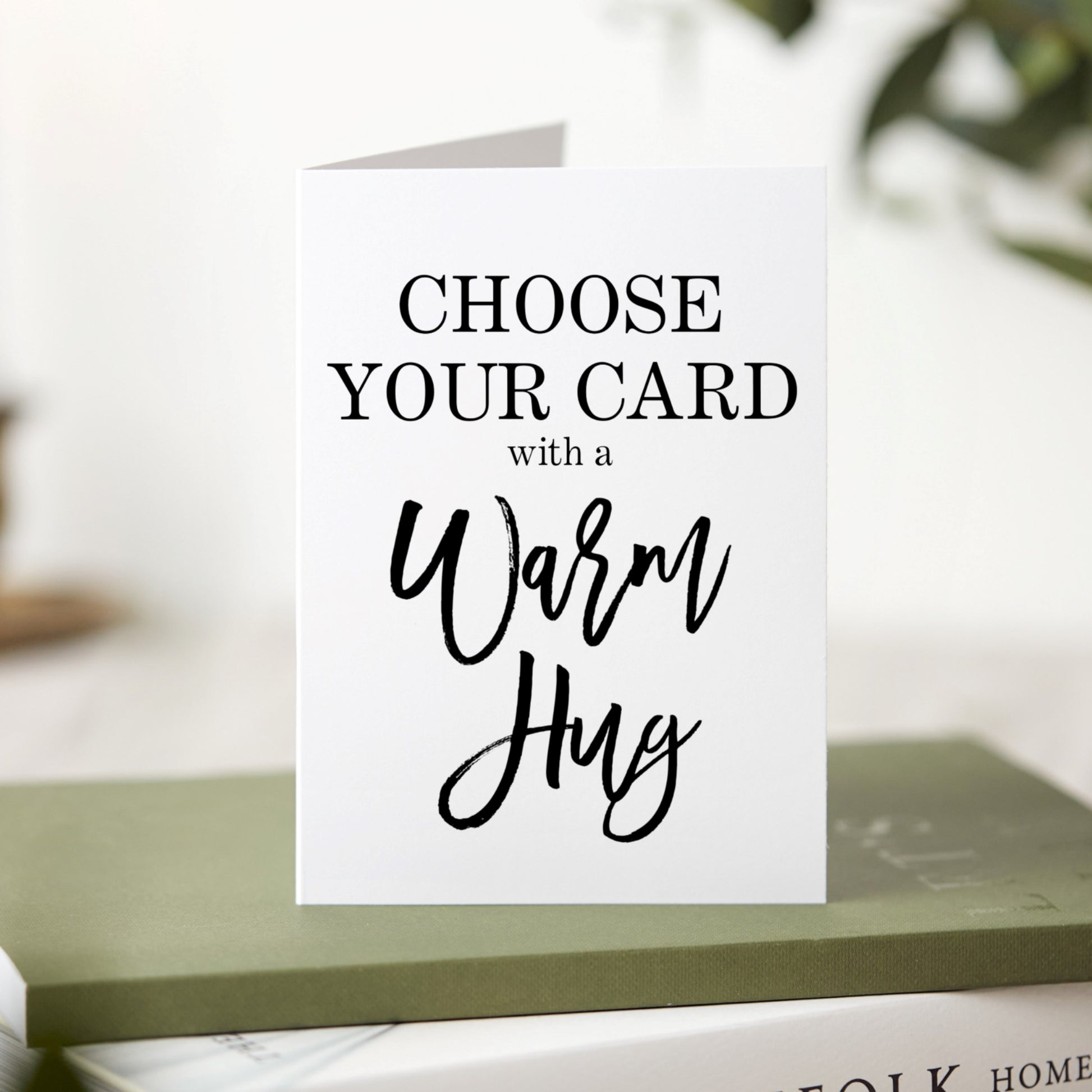 Greeting card with text 'Choose Your Card with a Warm Hug' on a blurred background