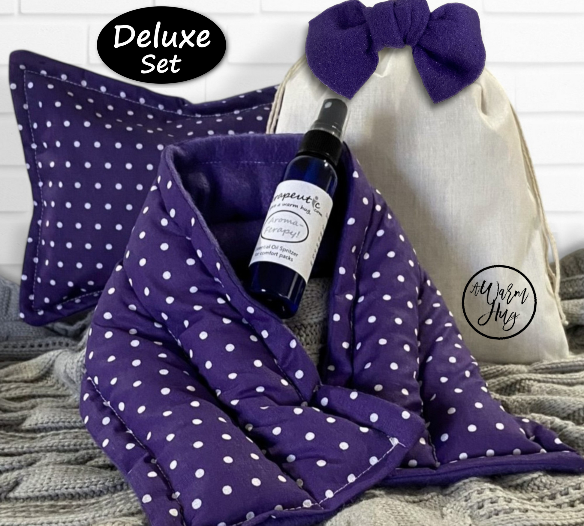 Purple polka dot hot cold packs with lavender essential oil spray and a white drawstring bag on a textured surface.