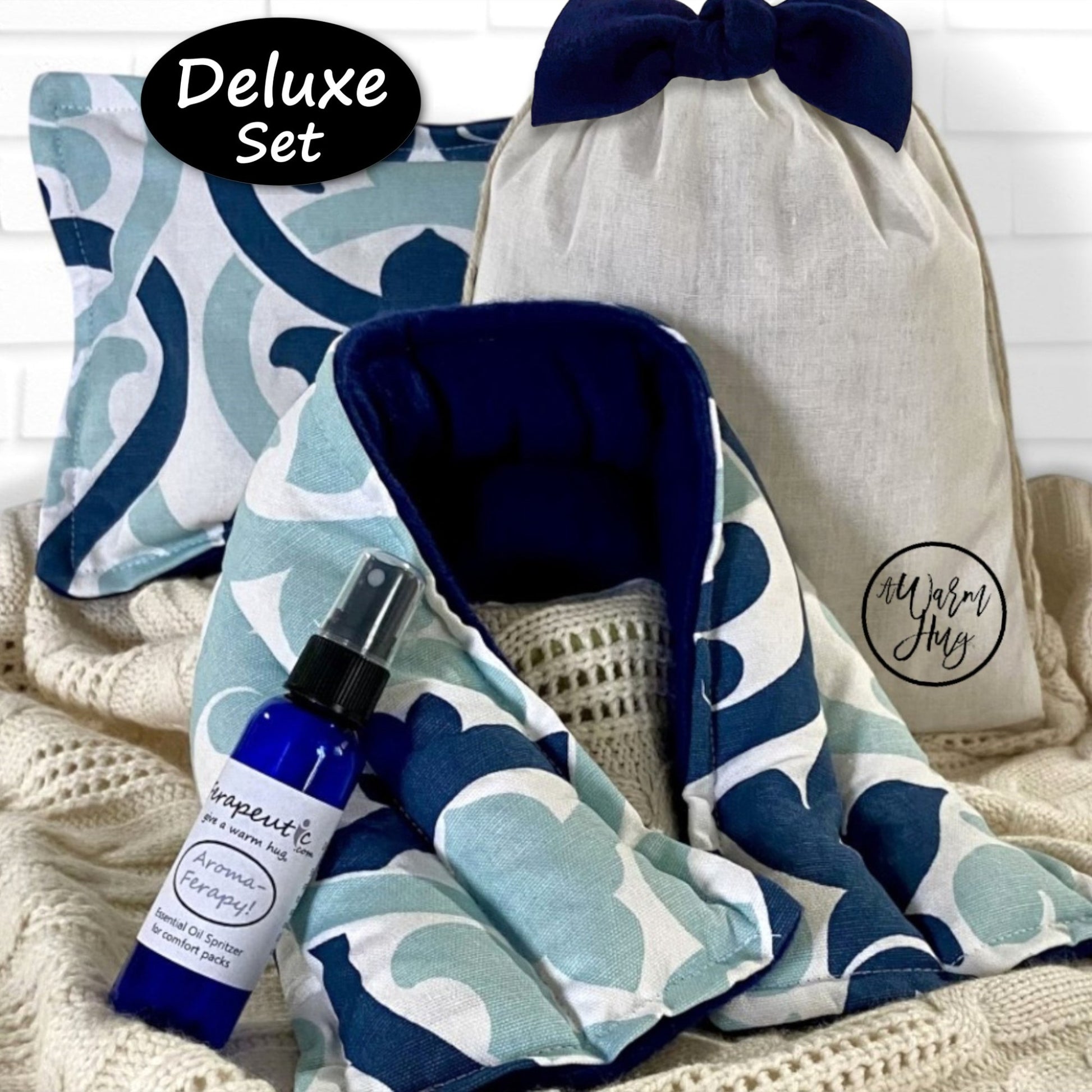 Deluxe set with microwavable neck wrap and heat pillow, and and essential oil lavender spray with 'Warm Hugs' on a textured surface.