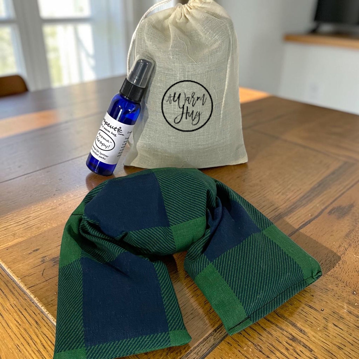 Image of green and blue plaid microwavable neck wrap with gift bag and aromatherapy spray bottle.