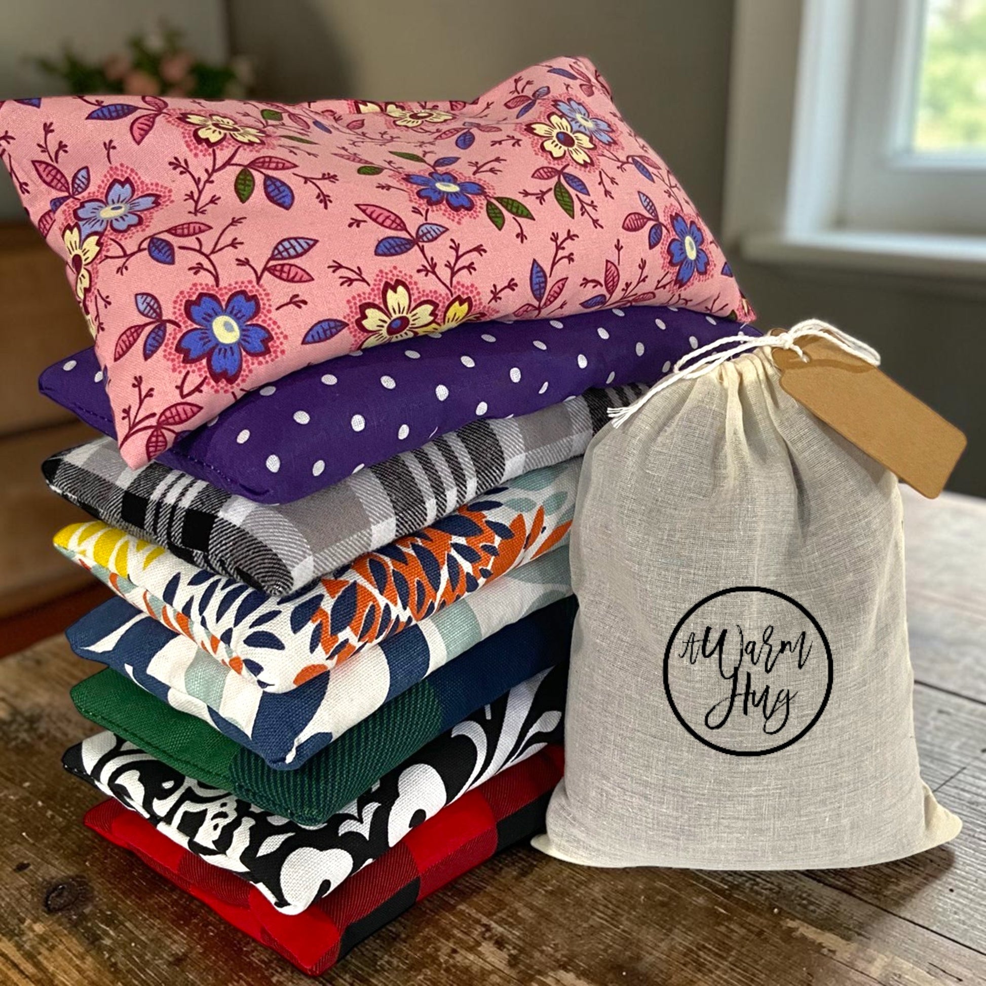 Stack of colorful hot cold packs with hand stamped warm hug gift bag and gift tag.