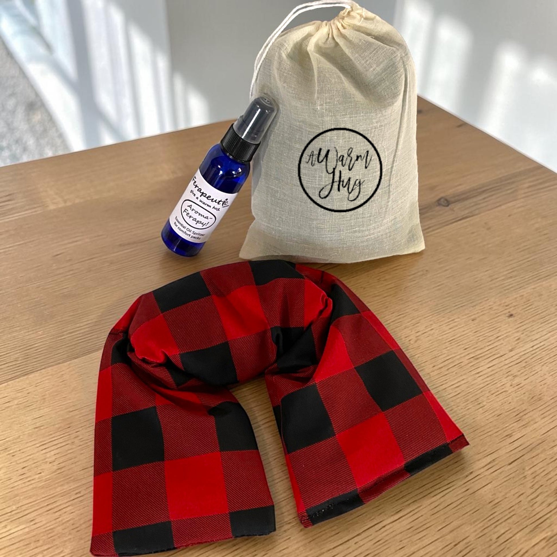 Image of red plaid microwavable neck wrap with gift bag and aromatherapy spray bottle.