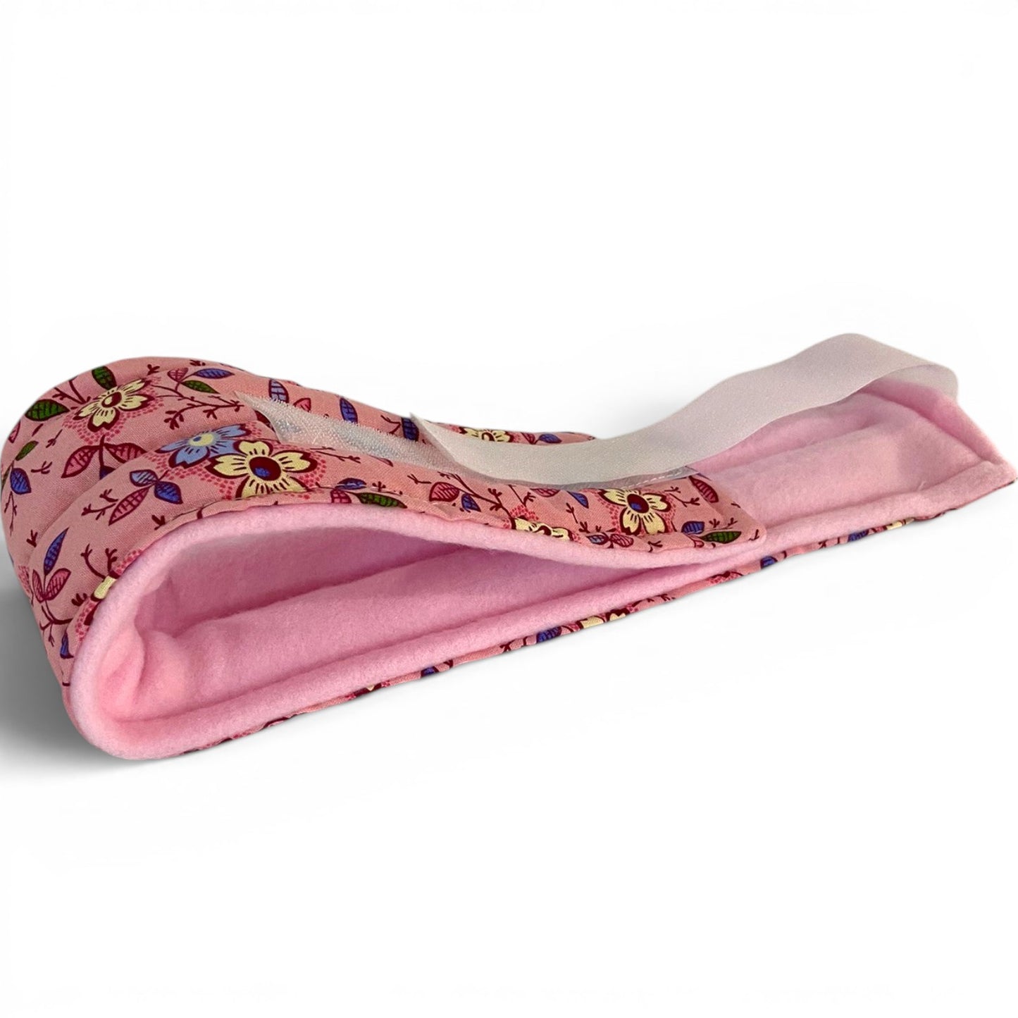 A rice and flax seed filled pink floral-patterned headband with a soft pink fleece lining, shown on a clean white background.  The head wrap can be used hot or cold for headaches, migraines, jaw pain, TMJ, TMDD and earaches.