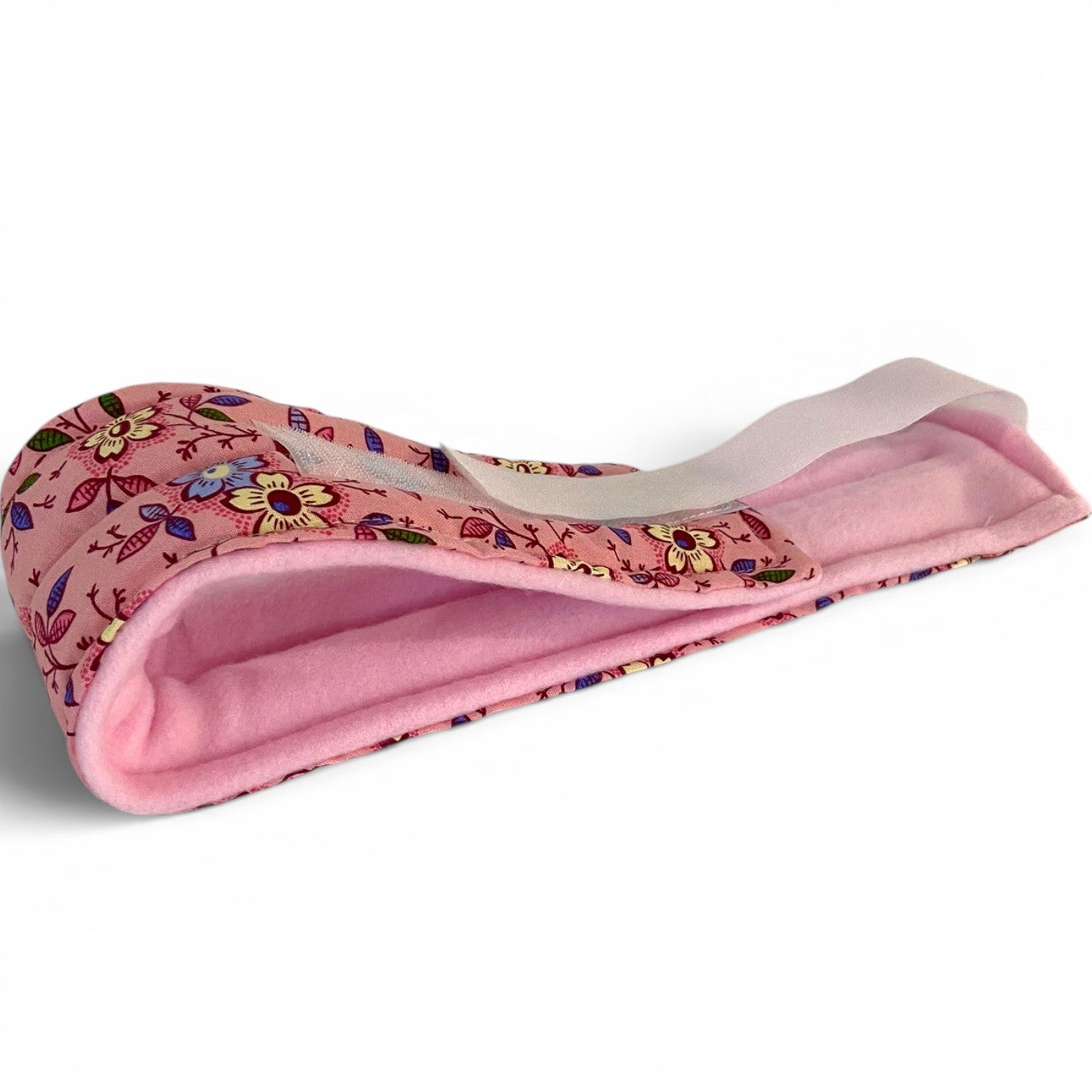 A rice and flax seed filled pink floral-patterned headband with a soft pink fleece lining, shown on a clean white background.  The head wrap can be used hot or cold for headaches, migraines, jaw pain, TMJ, TMDD and earaches.