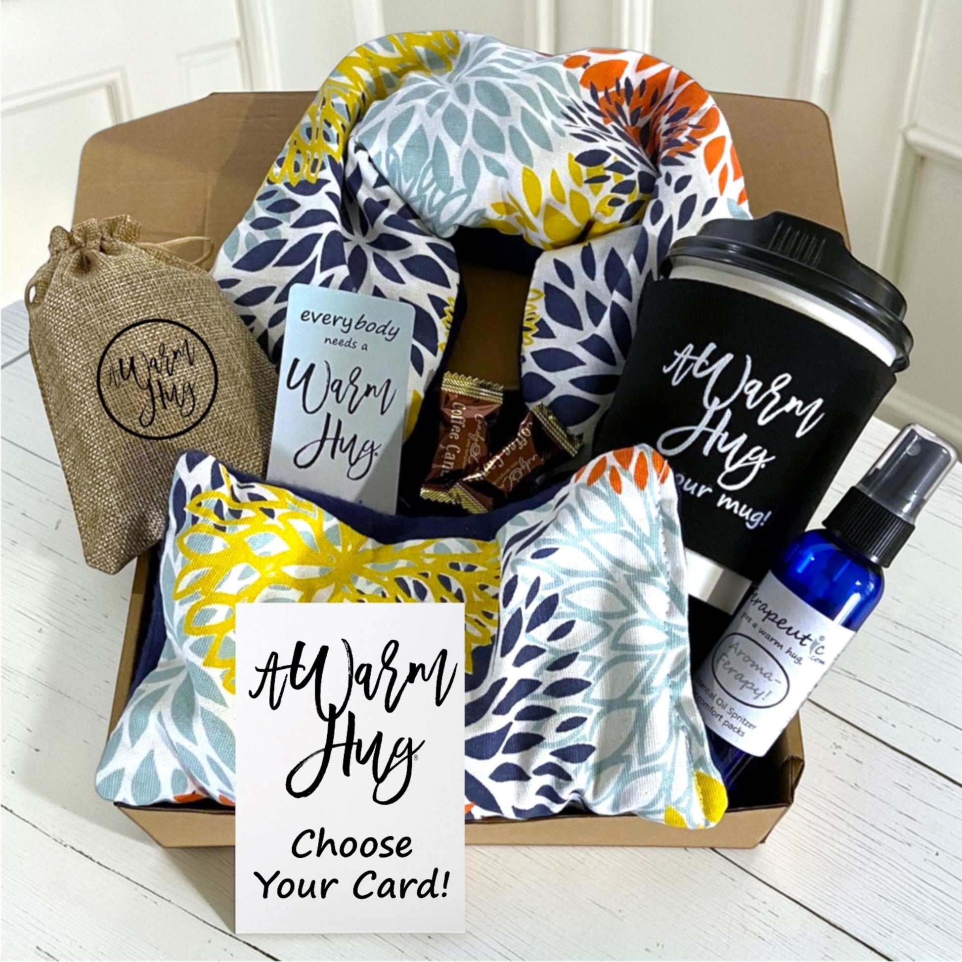 Gift box with warm hug blanket, mug, and other items on a wooden surface.