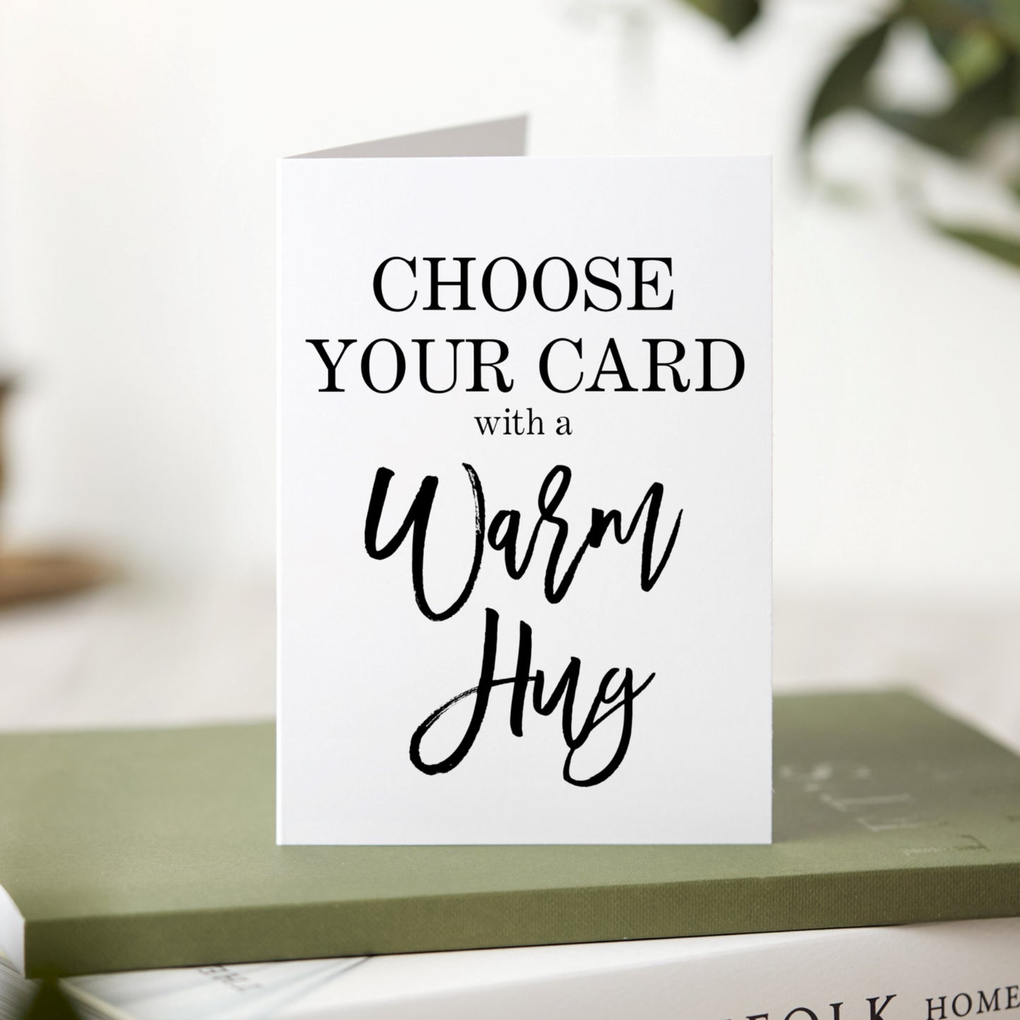 Greeting card with text 'Choose Your Card with a Warm Hug' on a blurred background
